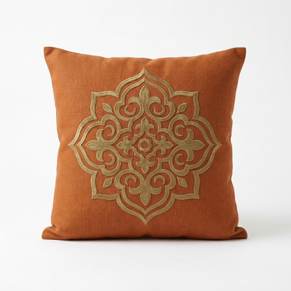 Burnt-orange linen pillow cover with antique gold embroidery, front view