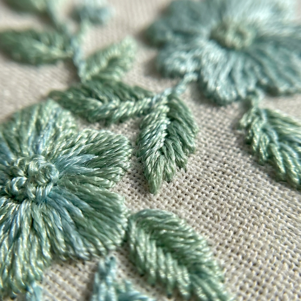 Close-up of mint silk embroidery on ivory linen